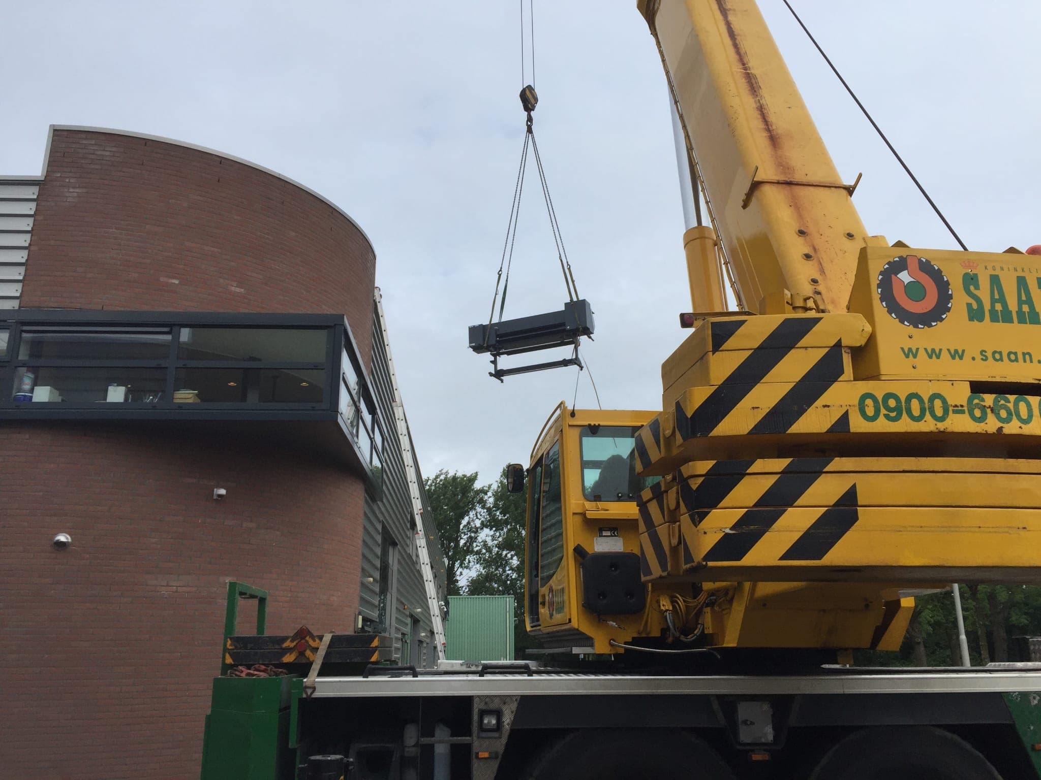 A printer being lifted out of the old building by crane during our 2020 move